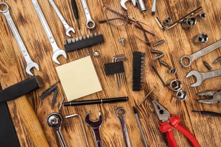 A wooden table displaying various tools alongside a notepad, suggesting a workspace for projects or repairs.
