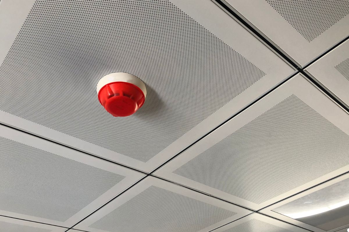Red fire alarm mounted on the ceiling of an office building, indicating fire safety measures in place.